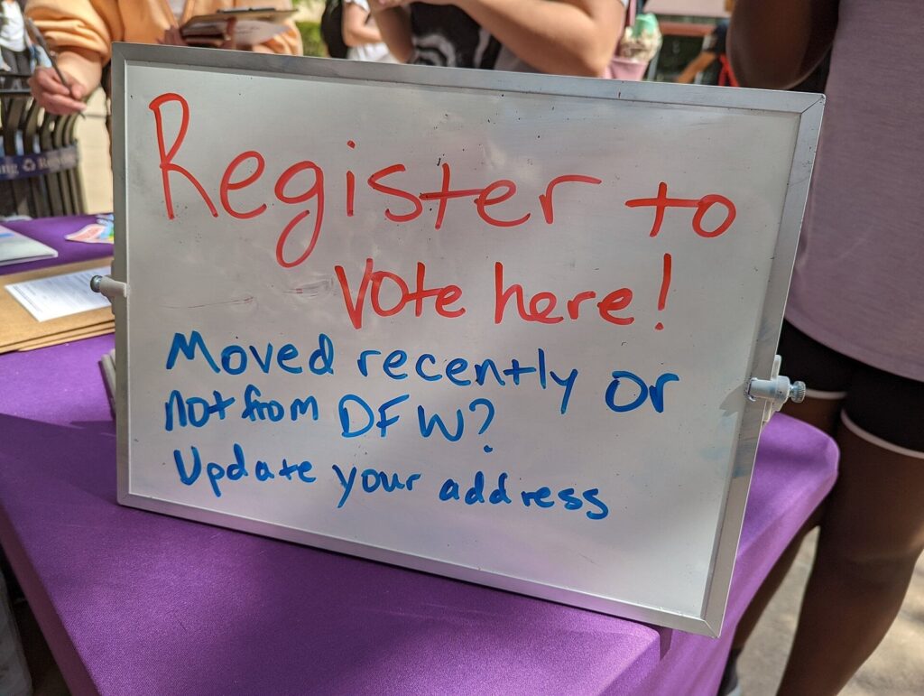 Voter registration sign at an outreach table